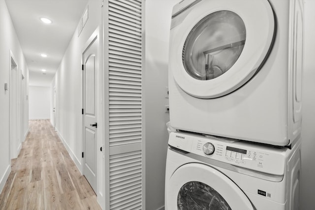 laundry room featuring laundry area, stacked washer and dryer, light wood-type flooring, baseboards, and recessed lighting