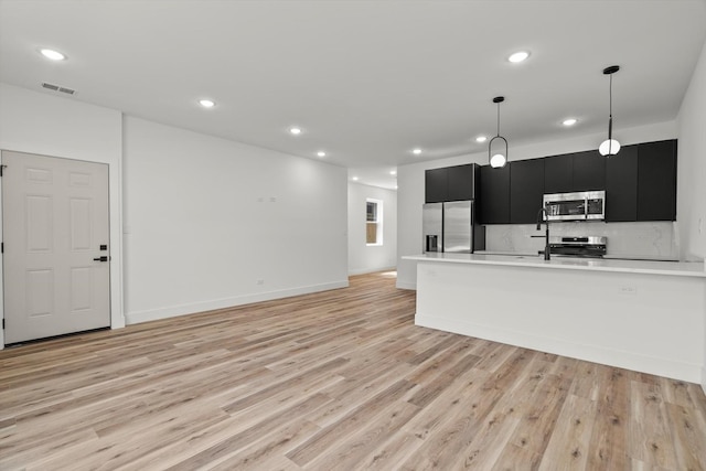 kitchen featuring visible vents, light wood-style floors, light countertops, dark cabinetry, and stainless steel appliances