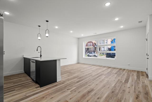 kitchen featuring a peninsula, light wood-style floors, recessed lighting, light countertops, and a sink