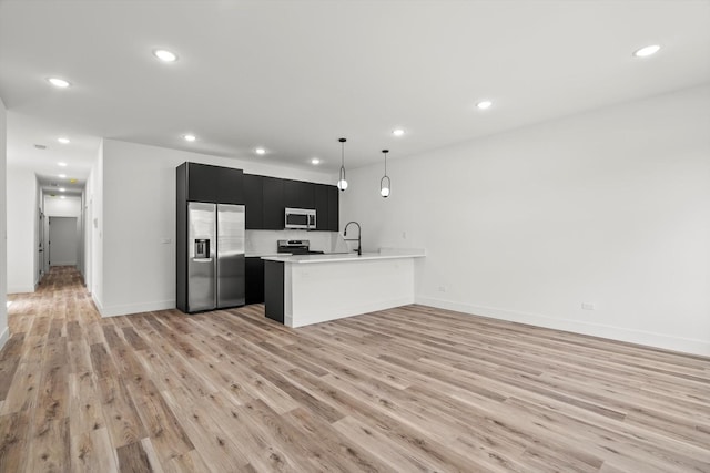kitchen featuring dark cabinetry, light wood-style floors, appliances with stainless steel finishes, and light countertops