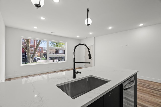 kitchen featuring recessed lighting, dark cabinetry, a sink, light wood-style flooring, and dishwasher