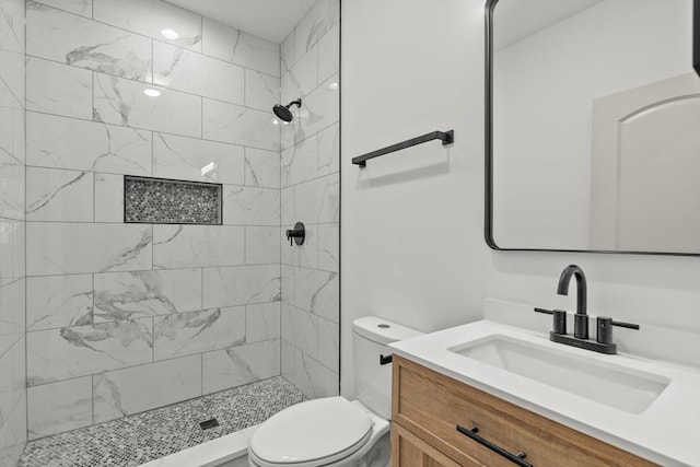full bathroom with vanity, a tile shower, and toilet