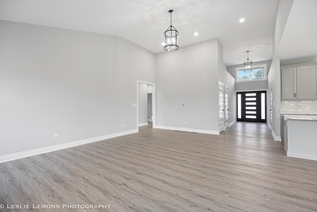 unfurnished living room with a notable chandelier, a high ceiling, and light wood finished floors