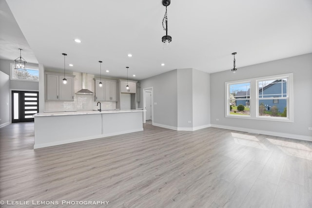 unfurnished living room featuring baseboards, light wood-type flooring, a sink, and recessed lighting