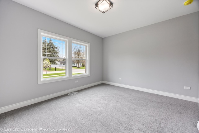 carpeted spare room with visible vents and baseboards