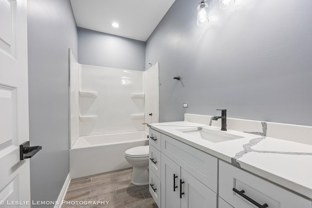 bathroom with toilet, wood finished floors, vanity, and bathtub / shower combination