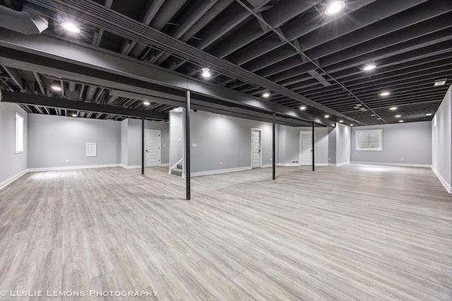 below grade area with baseboards, stairway, and wood finished floors