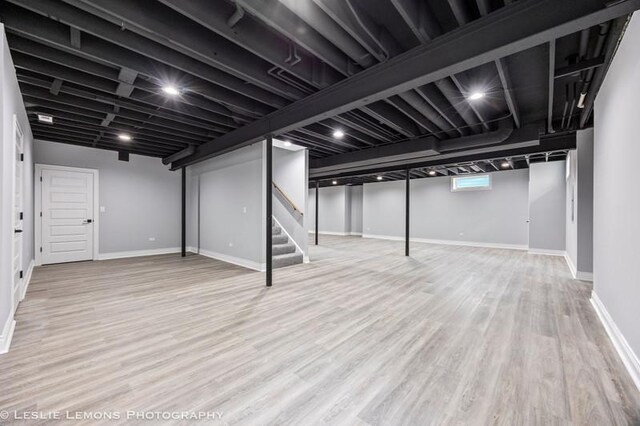 below grade area with stairway, wood finished floors, and baseboards