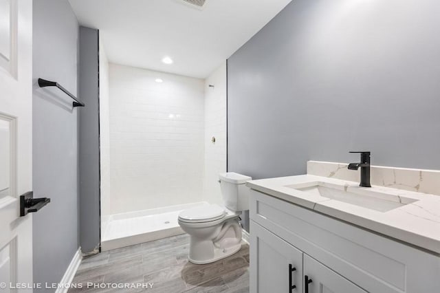 bathroom with a shower stall, vanity, toilet, baseboards, and wood finished floors