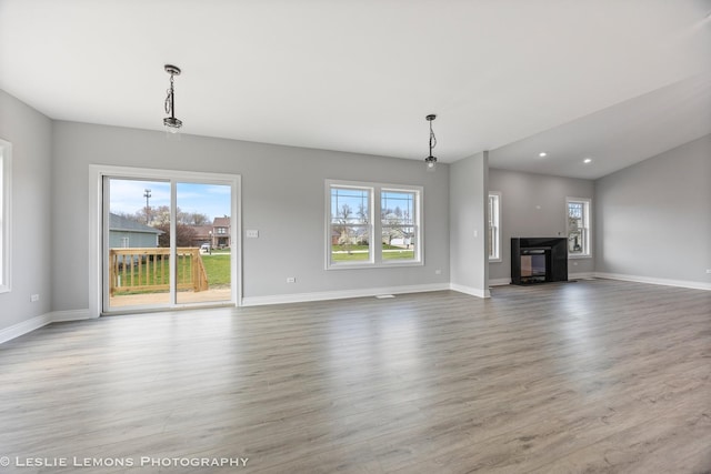 unfurnished living room featuring a glass covered fireplace, wood finished floors, recessed lighting, and baseboards