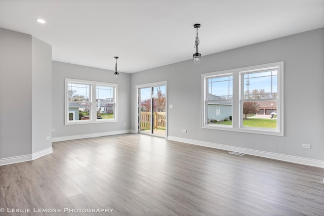 unfurnished dining area with wood finished floors, recessed lighting, visible vents, and baseboards