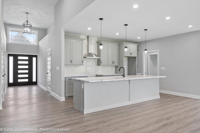 kitchen featuring gray cabinetry, recessed lighting, light wood finished floors, and wall chimney exhaust hood