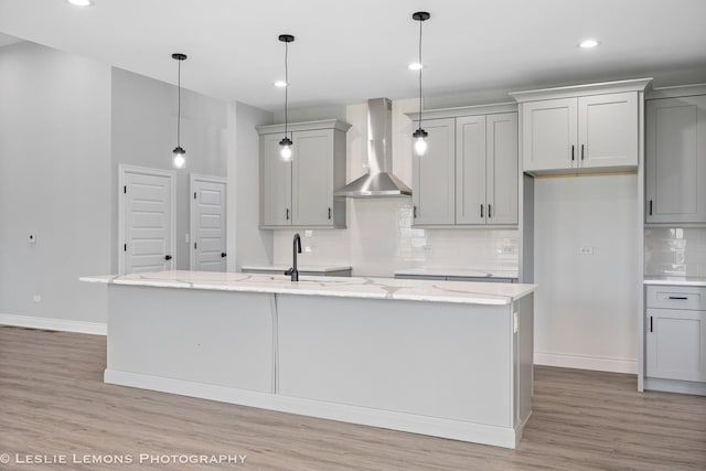 kitchen with gray cabinetry, baseboards, wall chimney exhaust hood, and light wood finished floors