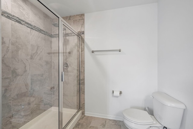 full bath featuring toilet, a stall shower, and baseboards