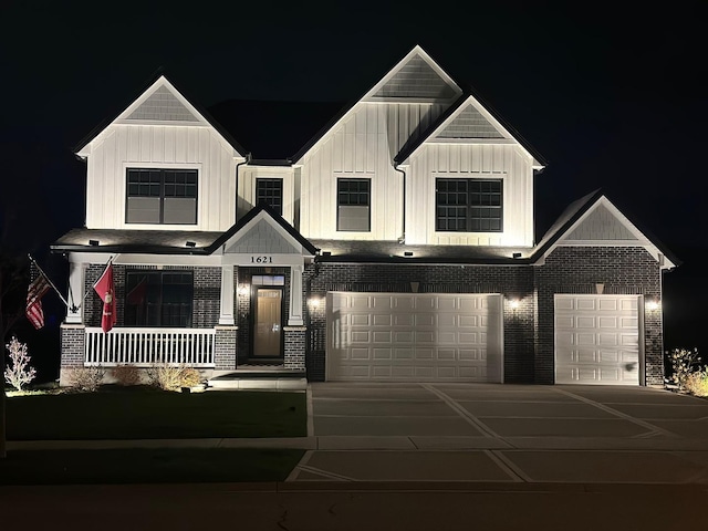 view of front of home with a garage, covered porch, board and batten siding, driveway, and brick siding