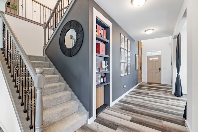 foyer entrance featuring wood finished floors, stairway, and baseboards