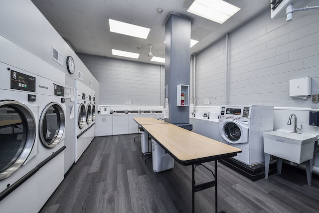 common laundry area with washer and dryer, a sink, dark wood finished floors, stacked washing maching and dryer, and visible vents