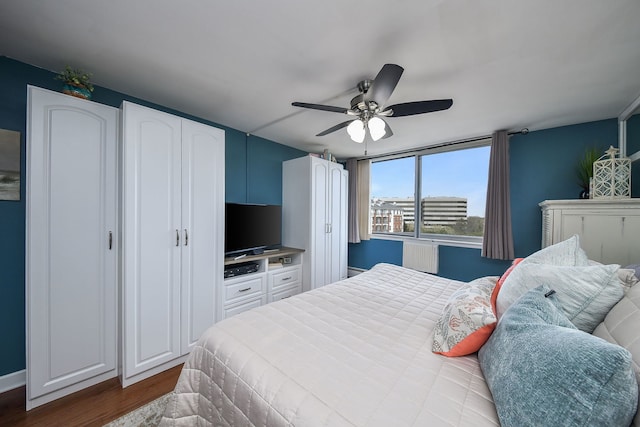 bedroom with ceiling fan, wood finished floors, and radiator