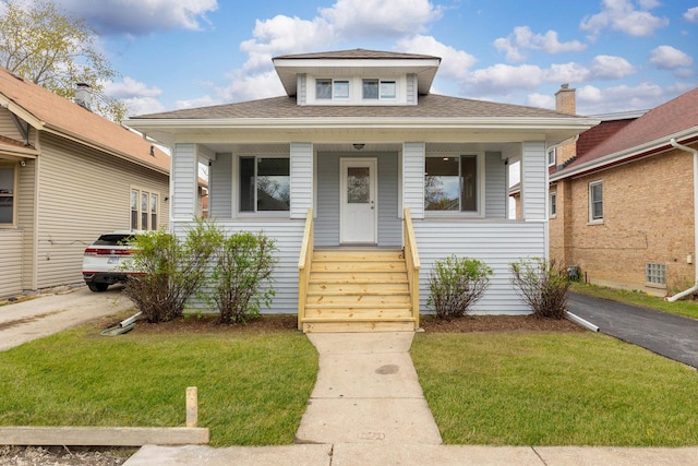 bungalow with roof with shingles, a front yard, and covered porch