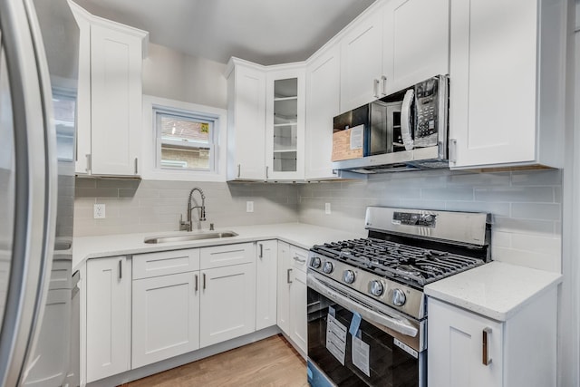 kitchen featuring white cabinets, tasteful backsplash, stainless steel appliances, and a sink