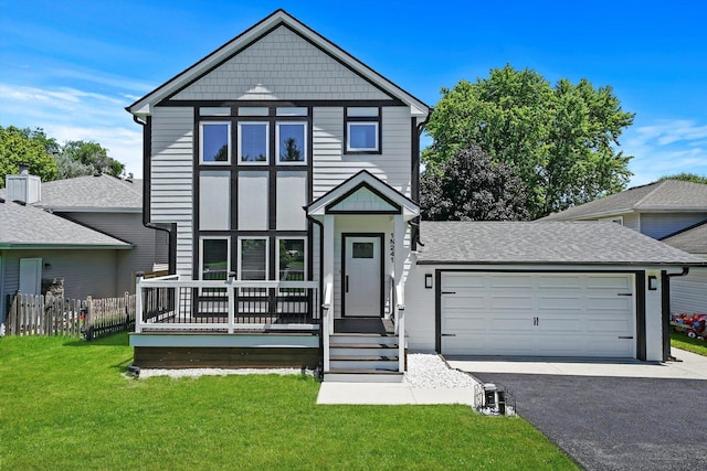 view of front of property with roof with shingles, fence, an attached garage, driveway, and a front yard