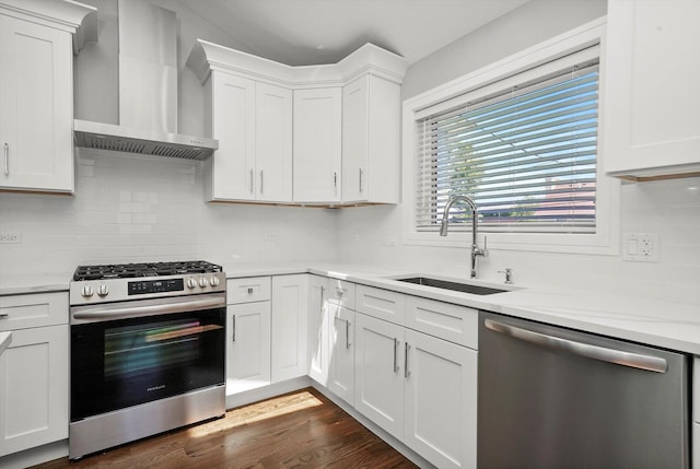 kitchen with a sink, stainless steel appliances, white cabinets, wall chimney range hood, and tasteful backsplash