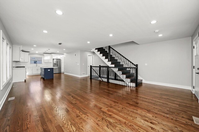 unfurnished living room featuring stairs, baseboards, dark wood-style floors, and recessed lighting