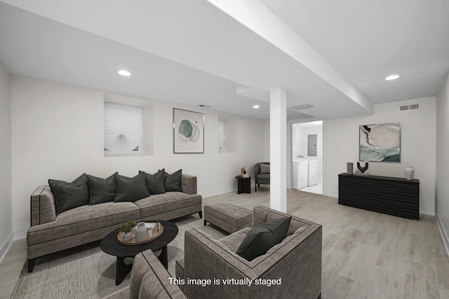 living area with washer and clothes dryer, visible vents, baseboards, and light wood-style floors
