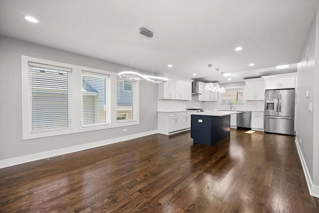 kitchen featuring an inviting chandelier, a center island, wall chimney exhaust hood, dark wood-style flooring, and appliances with stainless steel finishes