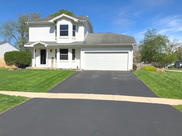 traditional home with asphalt driveway, an attached garage, and a front yard