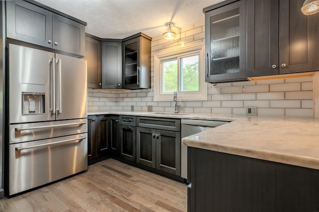 1306 Ewing St, Bloomington, IL 61701 - kitchen featuring decorative backsplash, appliances with stainless steel finishes, a sink, light countertops, and light wood-style flooring
