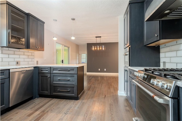 1306 Ewing St, Bloomington, IL 61701 - kitchen with light wood-style floors, a peninsula, tasteful backsplash, and stainless steel appliances