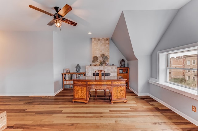 office featuring ceiling fan, baseboards, lofted ceiling, and light wood-type flooring
