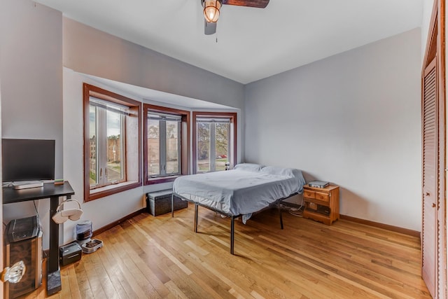 bedroom with light wood-style floors, ceiling fan, and baseboards