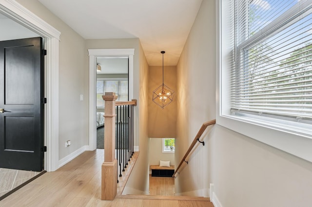 staircase with a notable chandelier, plenty of natural light, and wood finished floors
