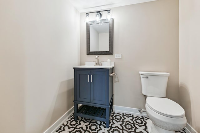 bathroom featuring toilet, baseboards, and vanity