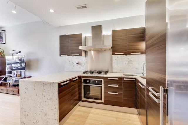 1811 W 17th St Unit 201, Chicago, IL 60608 - kitchen with decorative backsplash, visible vents, appliances with stainless steel finishes, a peninsula, and wall chimney exhaust hood