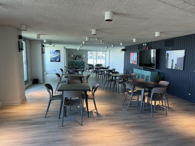dining room featuring light wood-type flooring and a textured ceiling