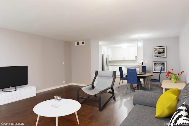 living room featuring baseboards, visible vents, and dark wood-style floors