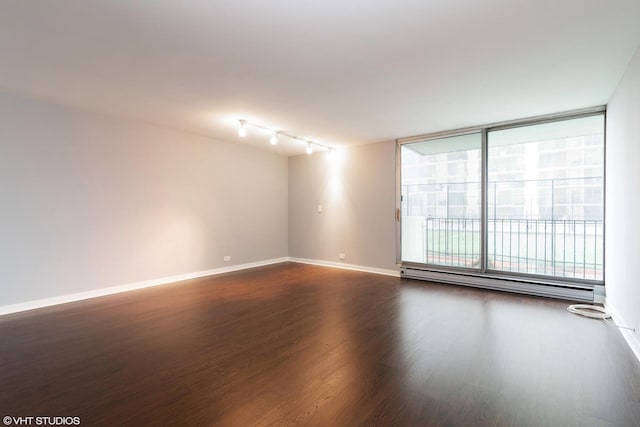 spare room featuring baseboards, baseboard heating, and dark wood-style flooring