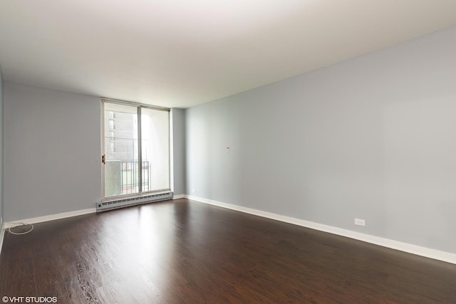 empty room featuring baseboards, dark wood finished floors, and baseboard heating