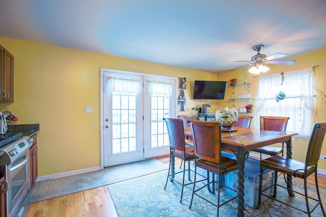 dining area featuring baseboards, light wood-type flooring, a ceiling fan, and a healthy amount of sunlight