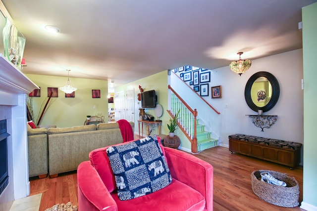 living area with wood finished floors, a tile fireplace, and stairs