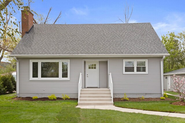 view of front of house with a detached garage, a chimney, an outdoor structure, and a front yard