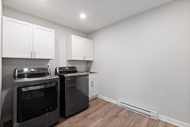 laundry area with washing machine and dryer, cabinet space, baseboards, a baseboard heating unit, and light wood-style floors