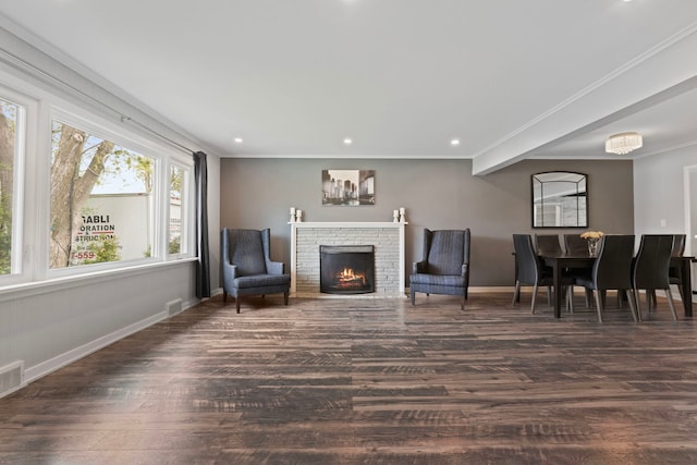 living area featuring wood finished floors, baseboards, a warm lit fireplace, ornamental molding, and recessed lighting