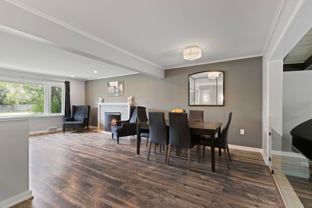 dining room featuring wood finished floors, visible vents, crown molding, baseboards, and a stone fireplace