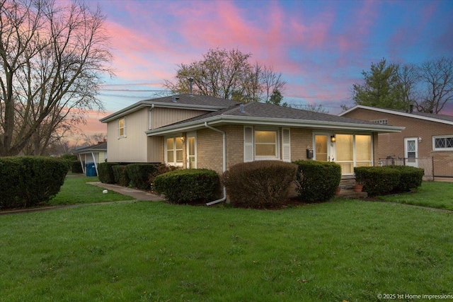 exterior space featuring brick siding and a yard