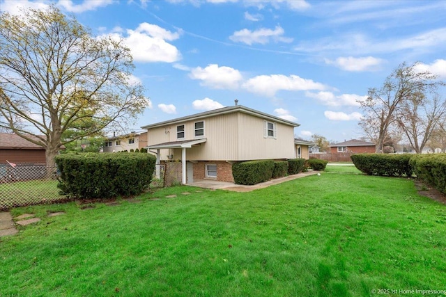 back of house featuring a lawn, fence, and brick siding