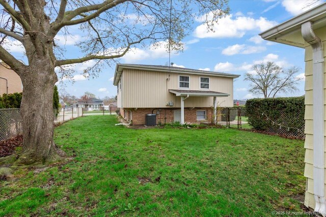 back of house with a yard, brick siding, cooling unit, and a fenced backyard